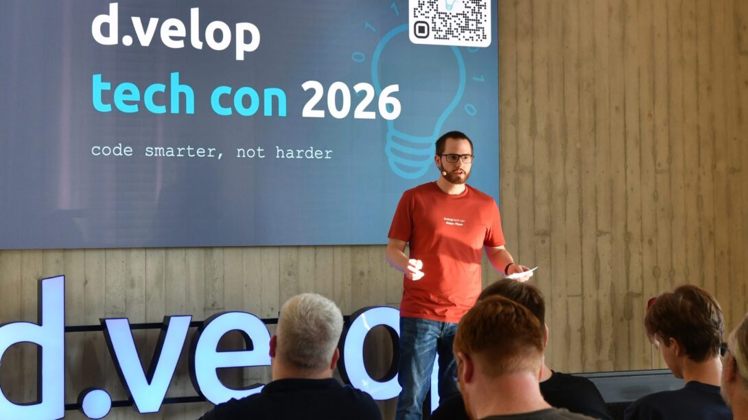 Moderator auf der Bühne der d.velop tech con 2026 vor dem Motto „code smarter, not harder“