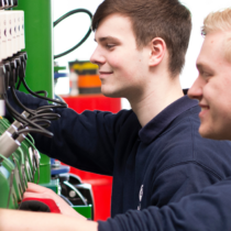Zwei Mitarbeitende arbeiten an technischen Systemen und greifen über eine Plattformlösung auf zentrale Dokumente zu, um Datensilos abzubauen