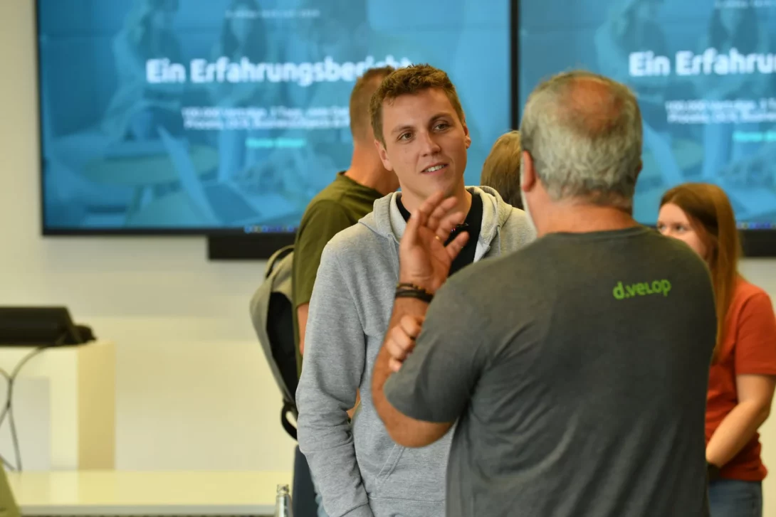 Gespräch zwischen Teilnehmenden nach einem Erfahrungsbericht auf der d.velop tech con 2026